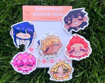 Könnte beinhalten: Eine Sammlung von Aufklebern im Anime-Stil mit Charakteren mit verschiedenen Haarfarben und Gesichtsausdrücken. Die Aufkleber sind auf einer weißen Karte angeordnet, mit einer rosa Karte mit der Aufschrift "Bakusquad Sticker Pack!" oben, vor einem grünen Gras Hintergrund.