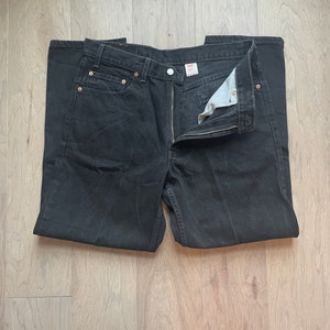 May include: A pair of black denim jeans with a button fly and a Levi's label on the back pocket.