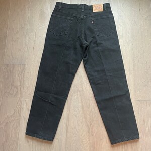 May include: A pair of black denim jeans with a Levi's label on the back pocket.