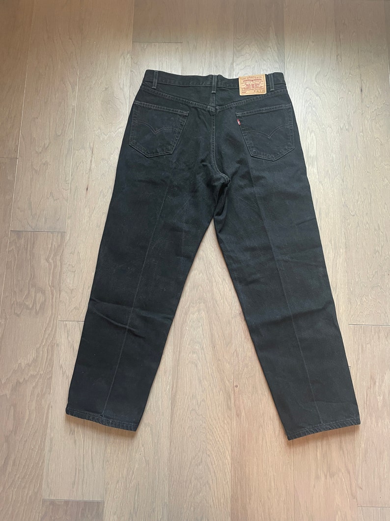 May include: A pair of black denim jeans with a Levi's label on the back pocket.
