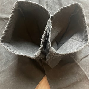 May include: Close-up of the inside of a pair of black denim jeans. The seams are visible and the fabric is soft and worn.