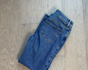 May include: A pair of blue denim jeans folded in half. The jeans have a back pocket.