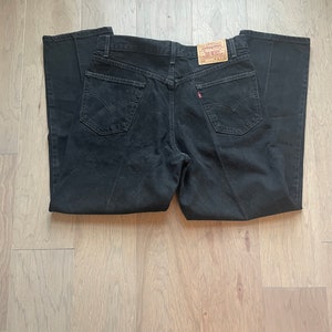 May include: Black denim jeans with a brown Levi's label on the back pocket.