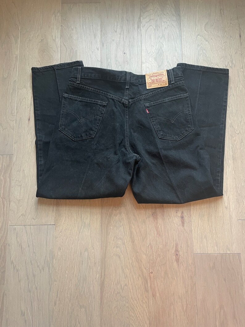 May include: Black denim jeans with a brown Levi's label on the back pocket.