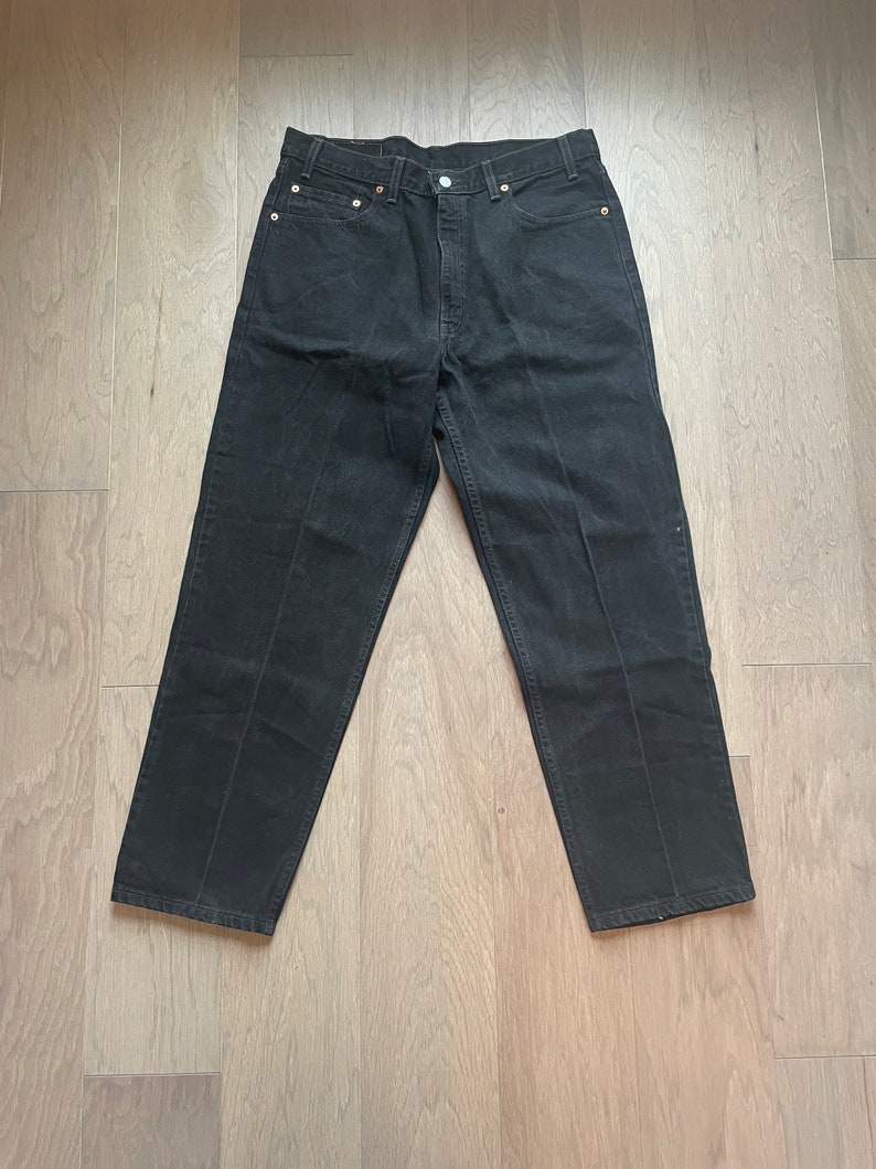 May include: Black denim jeans with a straight leg fit.