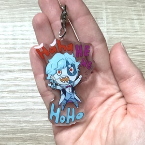Könnte beinhalten: Ein durchsichtiger Acryl-Schlüsselanhänger mit einer Comicfigur mit blauen Haaren und einem weißen und schwarzen Outfit. Die Figur lacht und der Text "Haha HE HE HoHo" ist auf dem Schlüsselanhänger aufgedruckt.