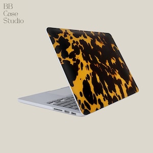 May include: A laptop with a tortoiseshell pattern on the lid. The design features a mix of black and yellow-brown spots. The laptop is open, revealing the keyboard and screen. The text "BB Case Studio" is in the upper left corner.