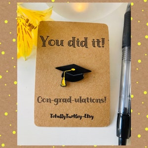 Könnte beinhalten: Eine braune Karte mit dem Text "You did it!" und "Con-grad-ulations!" mit einer schwarzen Graduation Cap mit einer gelben Quaste. Der Text "Totally Turtley-Etsy" befindet sich am unteren Rand der Karte.