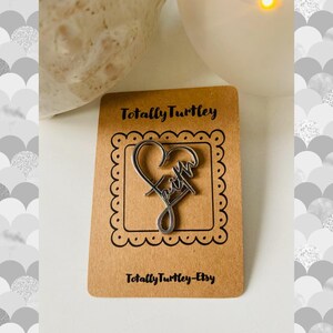Pu&ograve; includere: Un ciondolo d'argento a forma di cuore con la scritta "faith". Il ciondolo &egrave; esposto su una carta marrone con il testo "Totally Turtley-Etsy".