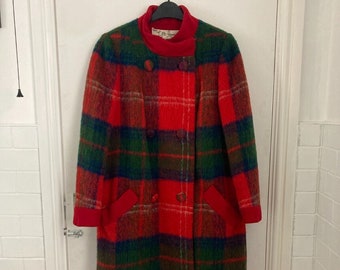 Könnte beinhalten: Ein roter, grüner und blauer karierter Wollmantel mit Stehkragen und doppelreihiger Knopfleiste. Der Mantel hat zwei Taschen und rote Einfassungen an den Ärmeln und Taschen.