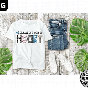 Op de afbeelding: Wit T-shirt met de tekst "Teaching is a work of heart" in kleurrijke letters met een luipaardprint. De letters zijn versierd met harten en andere patronen.