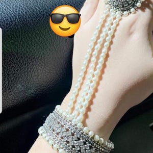 Może przedstawiać: Srebrna bransoletka z łańcuszkiem z białych pereł i srebrnym pierścionkiem z perełką i ozdobą z cyrkonii.