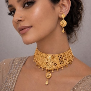 May include: A gold choker necklace featuring intricate filigree patterns, a central circular medallion, and a dangling teardrop charm, paired with matching circular drop earrings that have a small stud top and a delicate teardrop pendant.