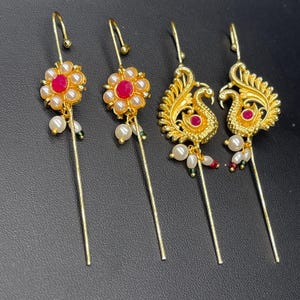 Pode incluir: Conjunto de três grampos de cabelo dourados com detalhes em pérolas e pedras preciosas vermelhas. Dois grampos apresentam um design de pavão e um grampo apresenta um design de flor.