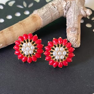 Puede incluir: Un par de pendientes de botón de flor roja y dorada con detalles de perlas blancas.