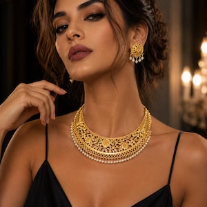 May include: A gold-toned crescent-shaped necklace featuring intricate floral filigree patterns and a delicate row of small white pearls along the bottom edge, paired with matching circular stud earrings that also feature pearls.