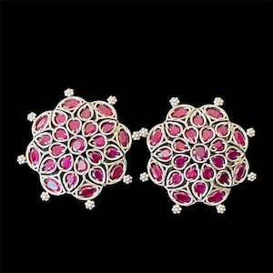 Può includere: Un paio di orecchini d'argento con un design floreale. Gli orecchini sono adornati con pietre preziose rosa.