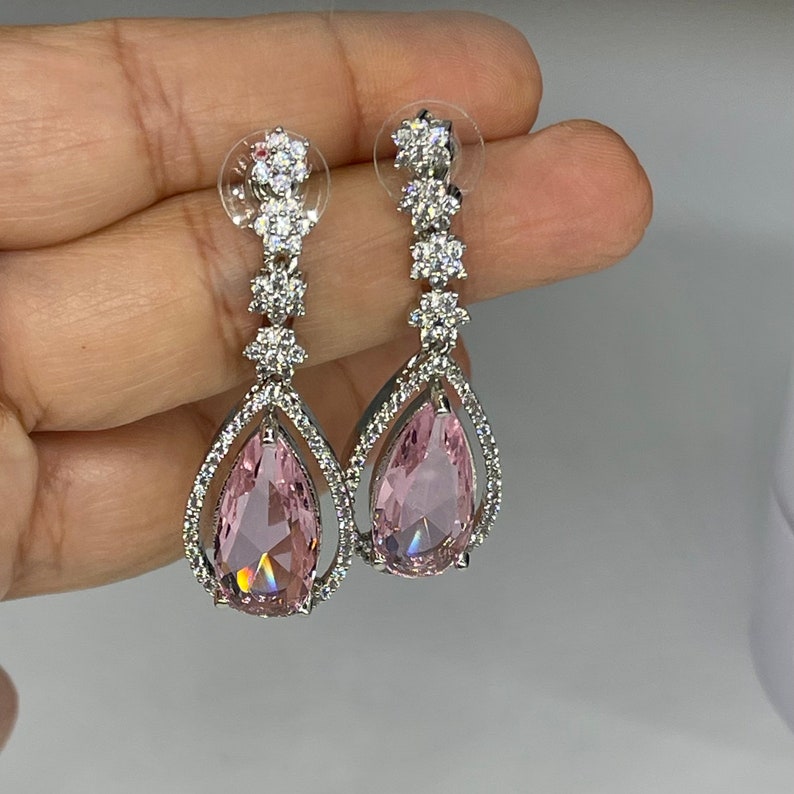 May include: A pair of silver teardrop earrings with pink pear-shaped stones and clear crystal accents.