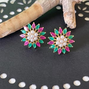 May include: A pair of gold earrings with a floral design. The earrings are made with pink and green gemstones and white pearls.