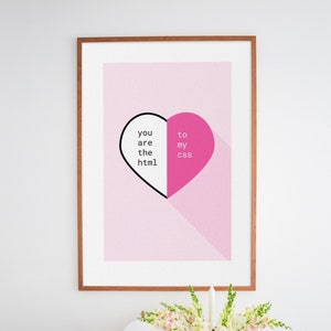 Op de afbeelding: Een ingelijst print met een roze achtergrond en een hartvorm die in tweeën is gedeeld. De linkerkant van het hart is zwart en zegt "you are the html" en de rechterkant is roze en zegt "to my css".