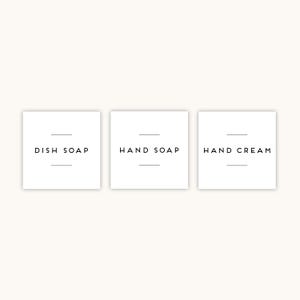 May include: Three white square labels with black text. The labels read "DISH SOAP", "HAND SOAP", and "HAND CREAM". Each label has a horizontal line above and below the text. The background is a light beige colour.