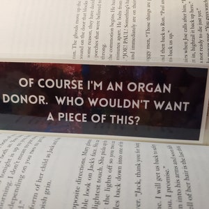 May include: A black and white bookmark with a colorful background. The bookmark features a bold white text that reads "Of course I'm an organ donor. Who wouldn't want a piece of this?"