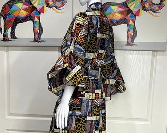 May include: A long, flowing maxi dress with a colorful geometric print. The dress has a ruffled hem and a fitted bodice. The print features a variety of colors, including blue, red, orange, yellow, and brown.