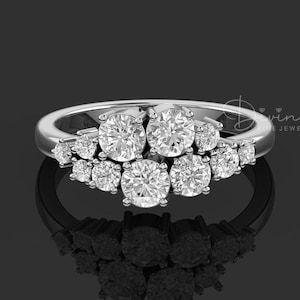 May include: A silver ring with a cluster of round diamonds set in a pave setting. The ring is on a black background.