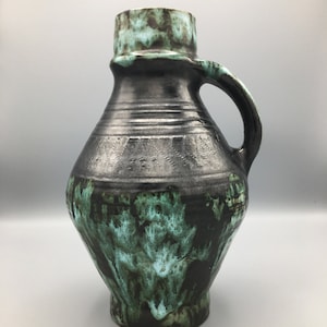 May include: A black and green ceramic vase with a handle. The vase has a mottled glaze with shades of green and black.