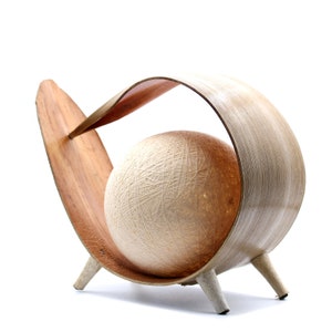 May include: A wooden lamp base with a curved design and three legs. A round, white, string-wrapped lampshade sits inside the base.