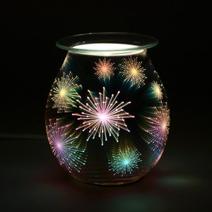 May include: A round glass oil diffuser with a black background and a colourful firework design. The diffuser has a white top and a light inside.