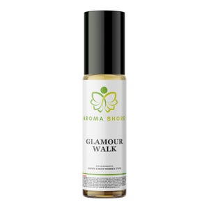 Puede incluir: Un frasco de perfume cilíndrico de vidrio con aplicador de bola, tapa negra y etiqueta blanca. La etiqueta muestra un logotipo de mariposa verde, el texto AROMA SHORE, GLAMOUR WALK y letra pequeña sobre el tipo de fragancia y la marca.