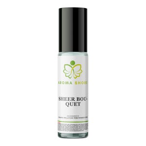 Pode incluir: Um frasco de perfume roll-on de vidro transparente com tampa cilíndrica preta. O rótulo branco apresenta um logótipo de borboleta verde, o texto AROMA SHORE, SHEER BOUQUET e letras pequenas sobre a inspiração da fragrância e o aviso legal.