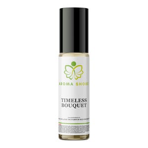 Pode incluir: Um frasco de perfume cilíndrico de vidro com aplicador roll-on e tampa preta. O rótulo branco apresenta um logótipo de borboleta verde, o texto AROMA SHORE, TIMELESS BOUQUET e letras pequenas incluindo OUR IMPRESSION OF NOEL NO 5 EAU DE PARFUM RED EDITION.
