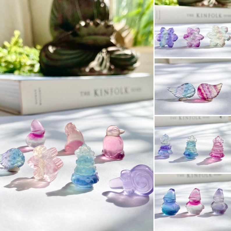 May include: A collection of colorful, iridescent glass figurines in various shapes, including a bird, a tree, a snowflake, a snail, and a butterfly. The figurines are arranged on a white surface with a soft, natural light.