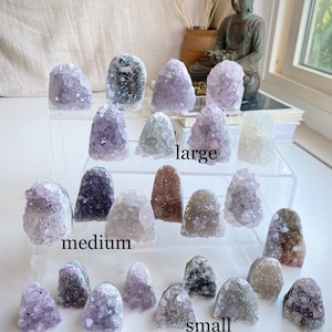 May include: A collection of amethyst crystal clusters in various sizes, labeled "large", "medium", and "small". The crystals are a light purple color and have a natural, rough texture.