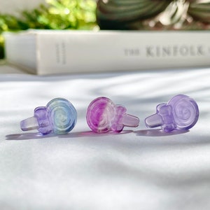 May include: Three small, colorful, glass snail figurines. The snails are iridescent and have a purple, blue, and green color gradient.
