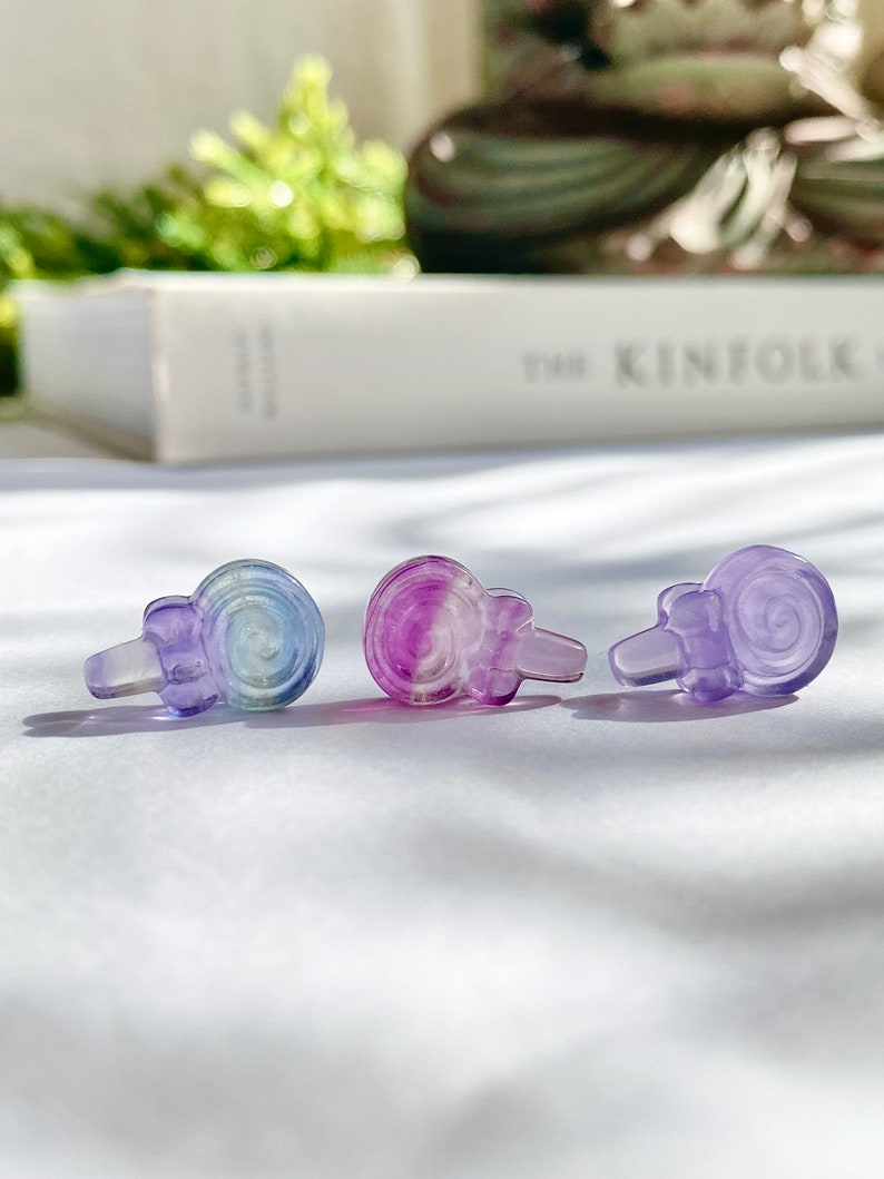 May include: Three small, colorful, glass snail figurines. The snails are iridescent and have a purple, blue, and green color gradient.