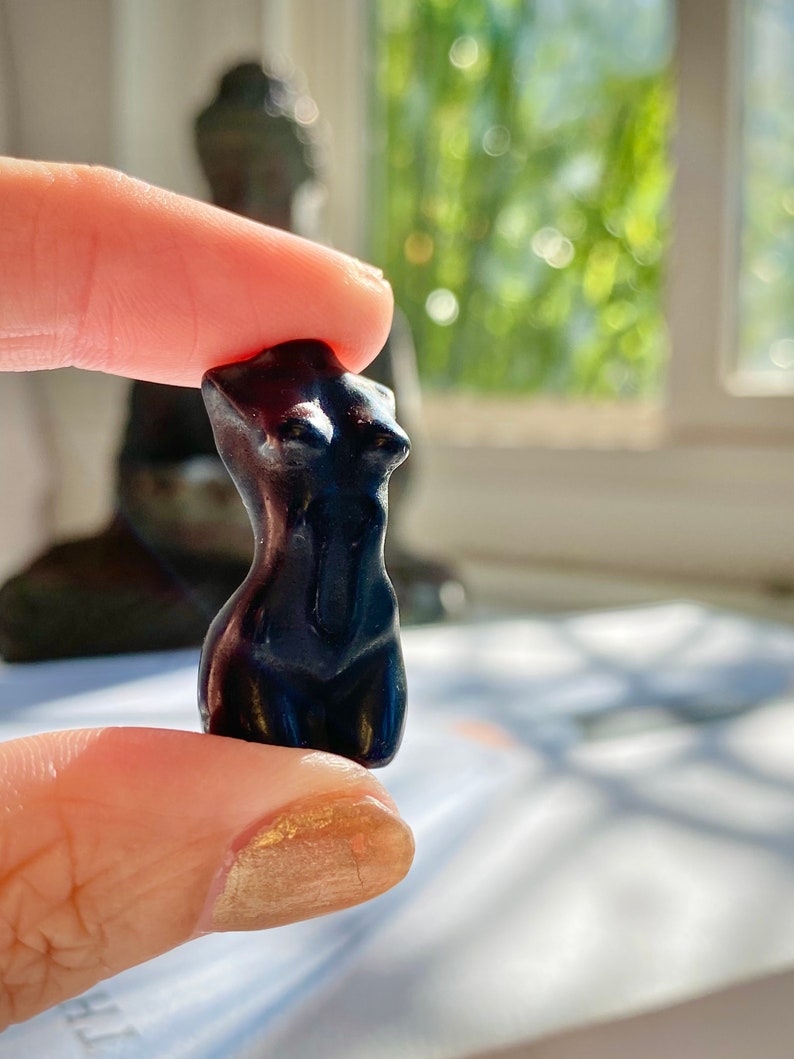 May include: A small, black, resin figurine of a female torso.