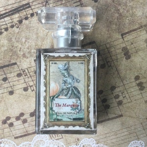 May include: A clear glass bottle of perfume with a gold label. The label features a vintage illustration of a woman in a dress and the text "The Marquise Eau de Parfum". The bottle is 1 oz (30 ml).