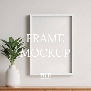 Puede incluir: Maqueta de marco de imagen blanco en una pared blanca con una planta verde en un jarrón blanco sobre un estante de madera. El texto "FRAME MOCKUP" está escrito en blanco en el marco. El texto "mv MOCKUP VISIONS" está escrito en blanco en la parte inferior del marco.
