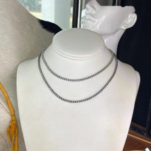 Peut inclure: Deux colliers de perles argent&eacute;s expos&eacute;s sur un buste de mannequin blanc. Les colliers sont compos&eacute;s de petites perles espac&eacute;es r&eacute;guli&egrave;rement, cr&eacute;ant une apparence d&eacute;licate et &eacute;l&eacute;gante. Le buste est plac&eacute; sur un fond neutre.
