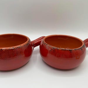 Puede incluir: Un juego de tres tazas de cerámica con un acabado mate moteado. Las tazas son de color crema, gris claro y gris oscuro. Cada taza tiene un diseño simple y minimalista y un asa redondeada.