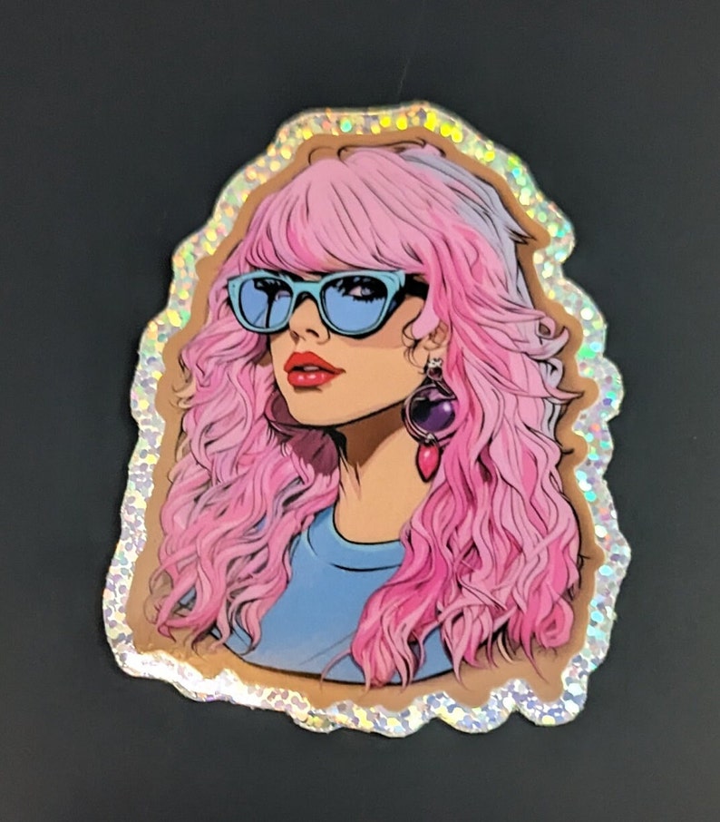 May include: A sticker featuring a cartoon illustration of a woman with pink hair, wearing blue sunglasses and a blue shirt. The sticker has a glittery, iridescent border.