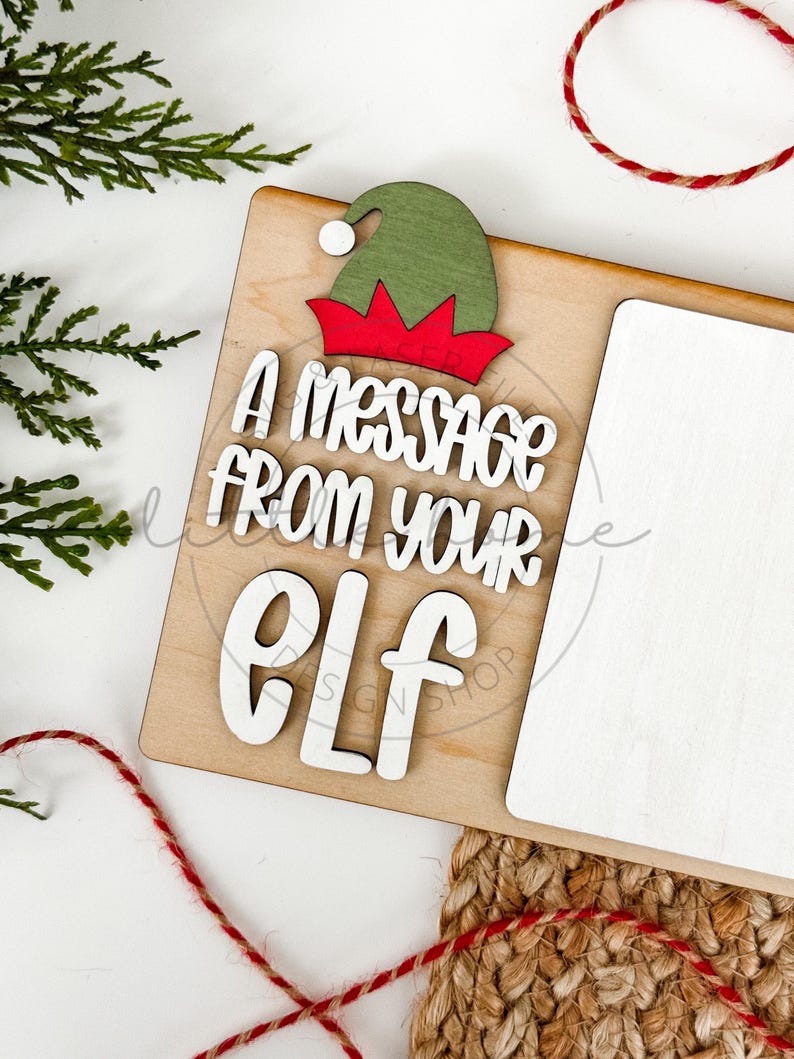 May include: A wooden sign with a green and red elf hat and the text "A message from your elf". The sign has a blank white space for writing a message.