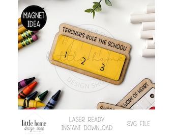 May include: A yellow and brown wooden ruler magnet with the text "Teachers Rule the School!" and the numbers 1, 2, and 3. The magnet is on a white surface with crayons and chalk.