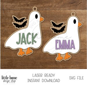 以下が含まれることがあります： 緑色の「Jack」と紫色の「Emma」という名前が付いた、ガチョウの形をした2つの木製オーナメント。各ガチョウは黒いコウモリの羽とオレンジ色の足とくちばしを持っています。オーナメントはレーザーカットされており、すぐにダウンロードできます。