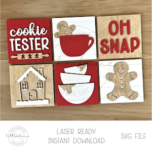 May include: Set of six wooden Christmas signs with red and white paint. The signs feature various Christmas-themed words and images, including "cookie tester", "oh snap", a gingerbread house, a gingerbread man, and a cup of hot chocolate.