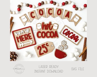 Könnte beinhalten: Ein Satz lasergeschnittener Holzschilder mit einem winterlichen Feiertagsmotiv. Die Schilder zeigen die Wörter "Cocoa", "Hot Cocoa", "Warm Up Here", "Cocoa" und "25¢". Die Schilder sind mit roter und weißer Farbe verziert, und einige haben kleine weiße Marshmallows.