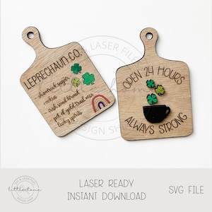Puede incluir: Dos letreros de madera con temática del Día de San Patricio. El primer letrero dice "Leprechaun Co." y enumera los ingredientes para el pote de oro de un duende. El segundo letrero dice "Abierto 24 horas Siempre fuerte" y presenta una taza de café negra con tréboles verdes.